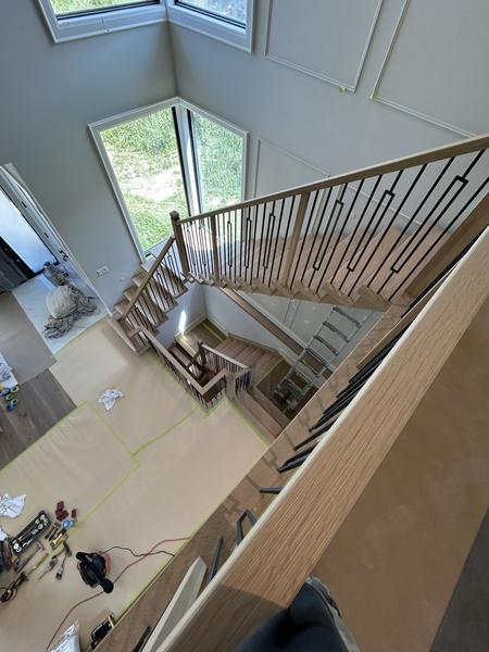 View from the upper landing onto an oak staircase with black iron balusters and panelled walls, floor masked