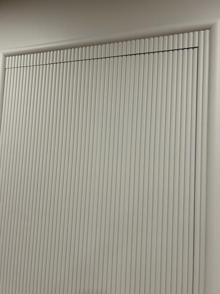 Close-up of a painted reeded wall panel in soft grey-white