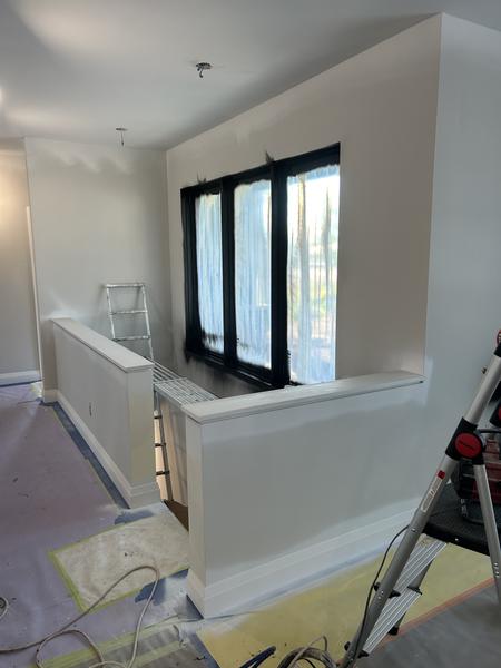 Half wall and window frames being sprayed black, floors and walls masked