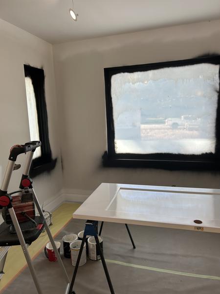 Window frames sprayed black with a door being finished on sawhorses