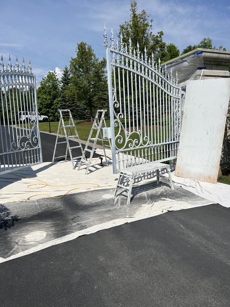 Wrought-iron driveway gate primed silver during refinishing